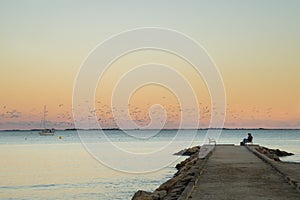 At sunset, people sit on a bench on the pontoon on Capri Beach photo